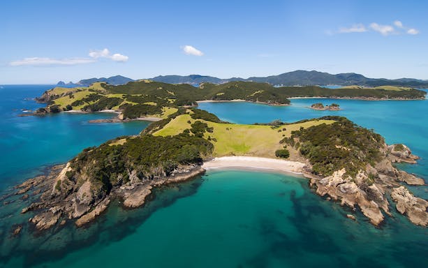 Aerial view of Bay of Islands with lush greenery and turquoise waters, New Zealand.