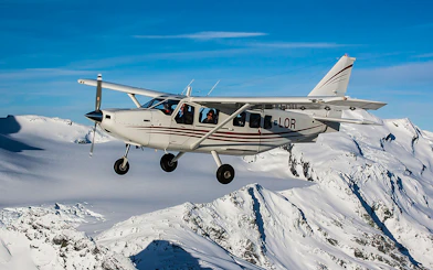 Small plane flying over snow-covered mountains near Mt Cook, New Zealand.