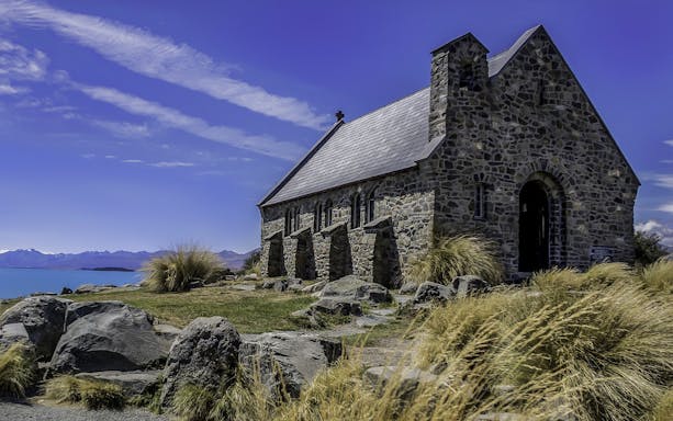 Stone church near Lake Tekapo with mountain backdrop on Mt Cook tour from Christchurch.