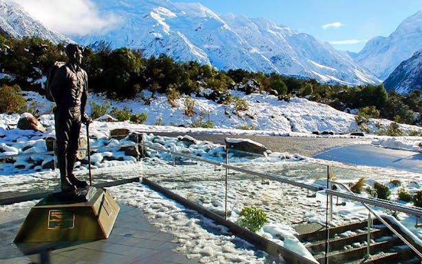 Statue of a hiker with snowy Mt Cook backdrop on tour from Christchurch.