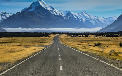 Open road leading to Mt Cook with snow-capped peaks, viewed from Lake Tekapo area.