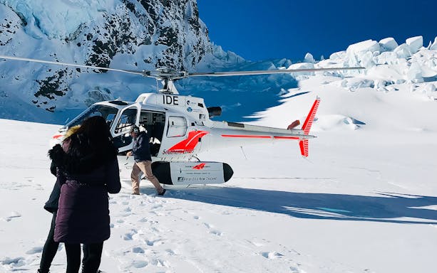 Helicopter landing on snowy terrain during Mt Cook tour from Christchurch.