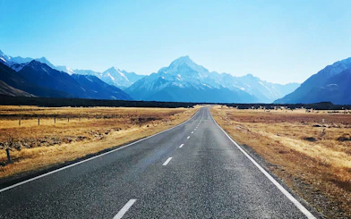 Open road leading to Mt Cook with snow-capped peaks, viewed from Christchurch tour route.