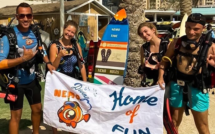 Divers holding a "Nemo Diving" banner at a PADI course in Dubai.
