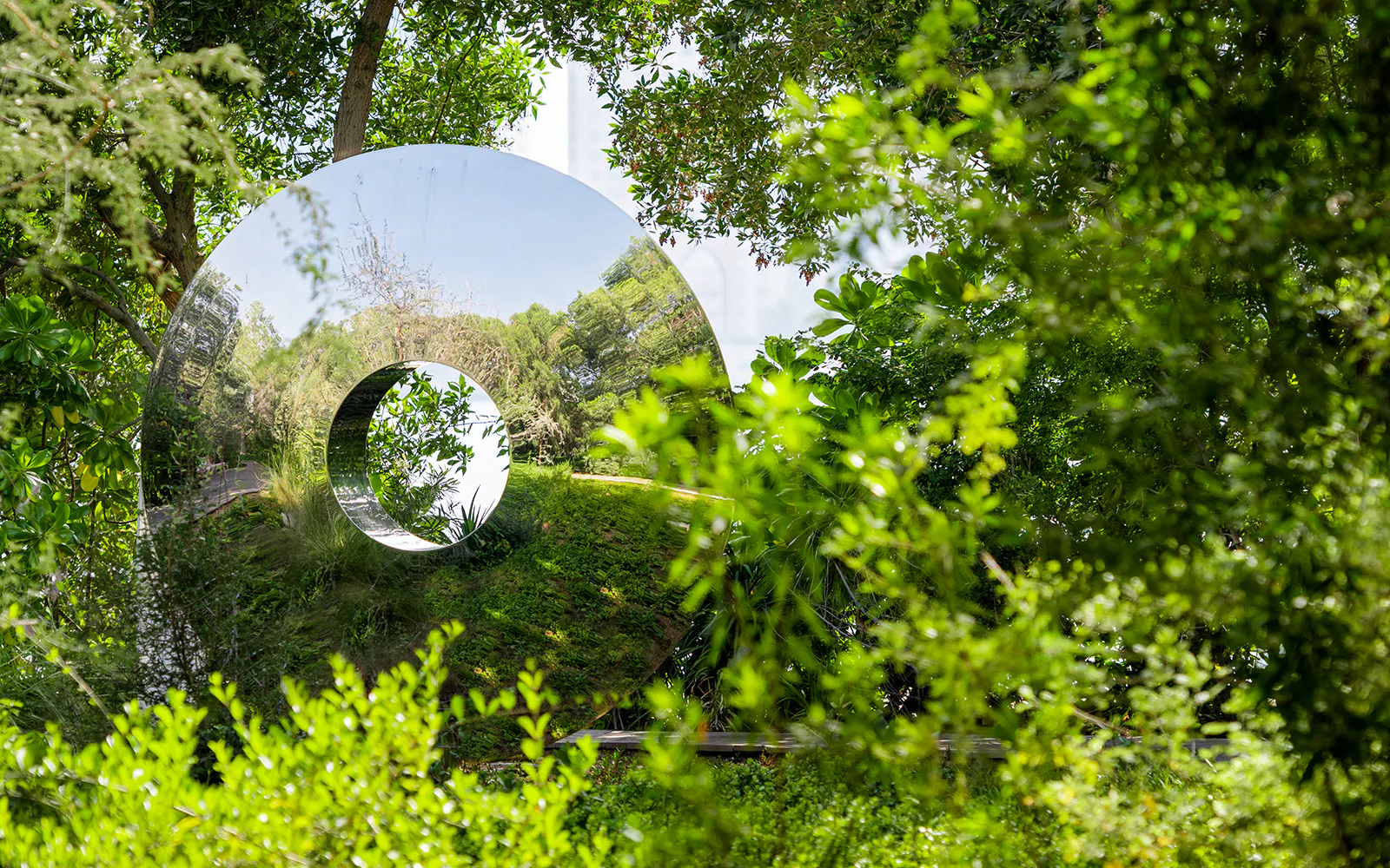 Reflective sculpture surrounded by lush greenery on Al Noor Island, Sharjah.