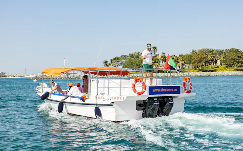 Private small group on a boat cruise in Dubai with UAE flag and coastal view.