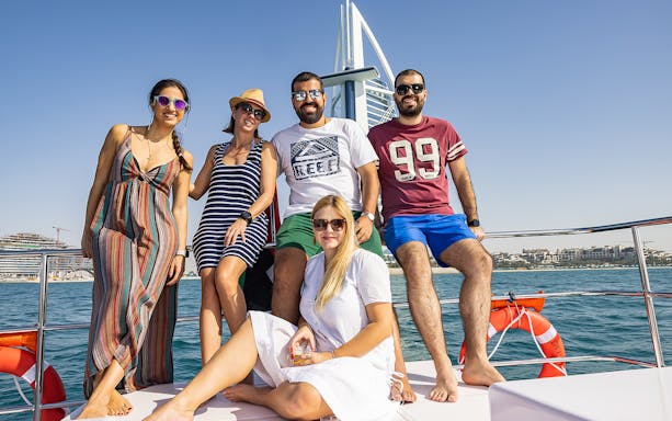 Group enjoying a private cruise with Burj Al Arab in the background, Dubai.