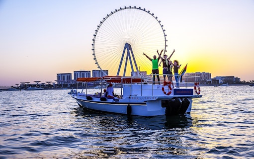 Private group enjoying a Dubai cruise with Ain Dubai in the background at sunset.