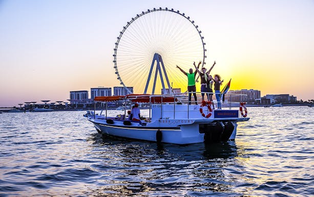 Private group enjoying a Dubai cruise with Ain Dubai in the background at sunset.
