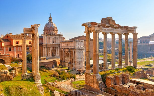 Roman Forum ruins with ancient columns and historic buildings, Rome, Italy.