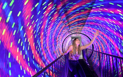 Visitor enjoying colorful vortex tunnel at Museum of Illusions Kuala Lumpur.