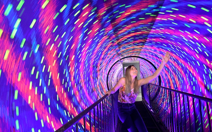 Visitor enjoying colorful vortex tunnel at Museum of Illusions Kuala Lumpur.