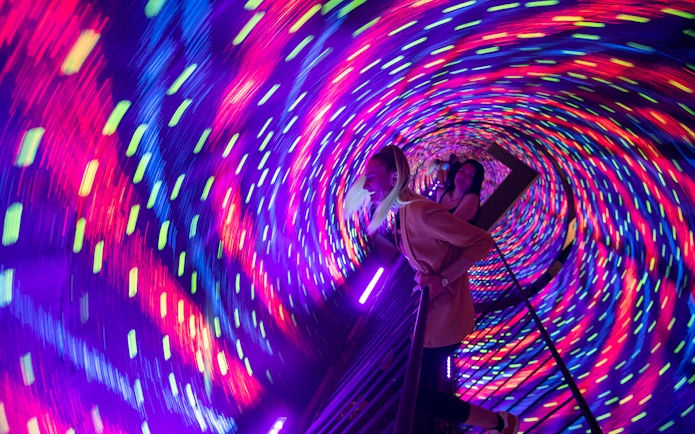 Visitors in a colorful vortex tunnel at Museum of Illusions Kuala Lumpur.