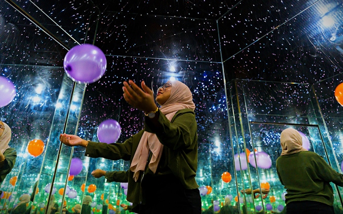 Person in mirrored room with balloons at Museum of Illusions Kuala Lumpur.