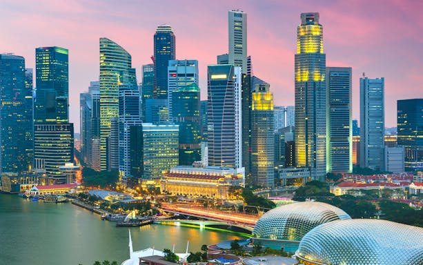 Singapore skyline at dusk with Marina Bay Sands and Esplanade theaters, highlighting cityscape.