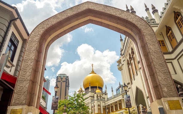 Sultan Mosque's golden dome framed by an ornate arch in Singapore.