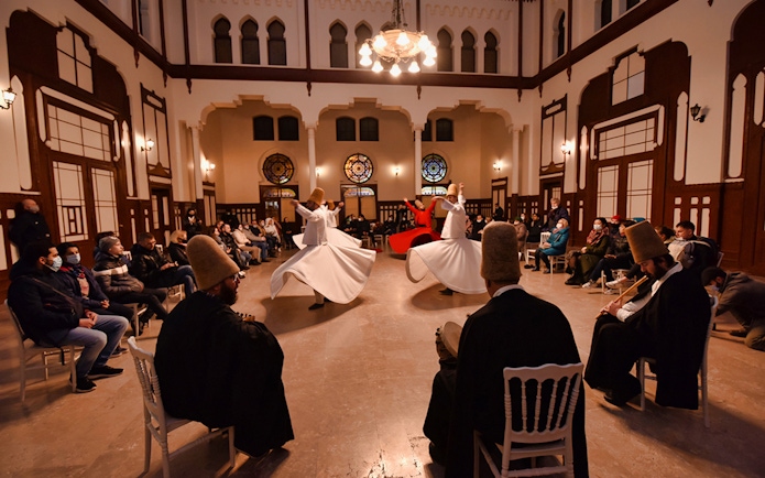 Whirling dervishes performing Sufi dance in a hall with an audience, Istanbul.