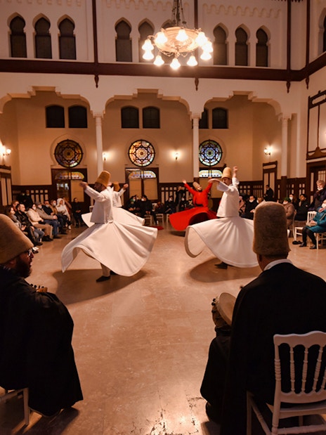 Whirling dervishes performing Sufi dance in a hall with an audience, Istanbul.