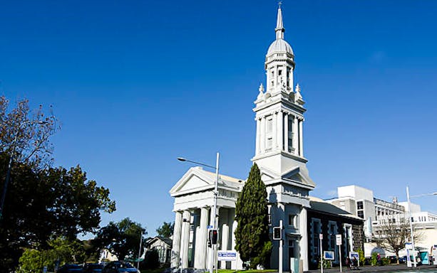 Historic church with tall spire on a street in Auckland, New Zealand.