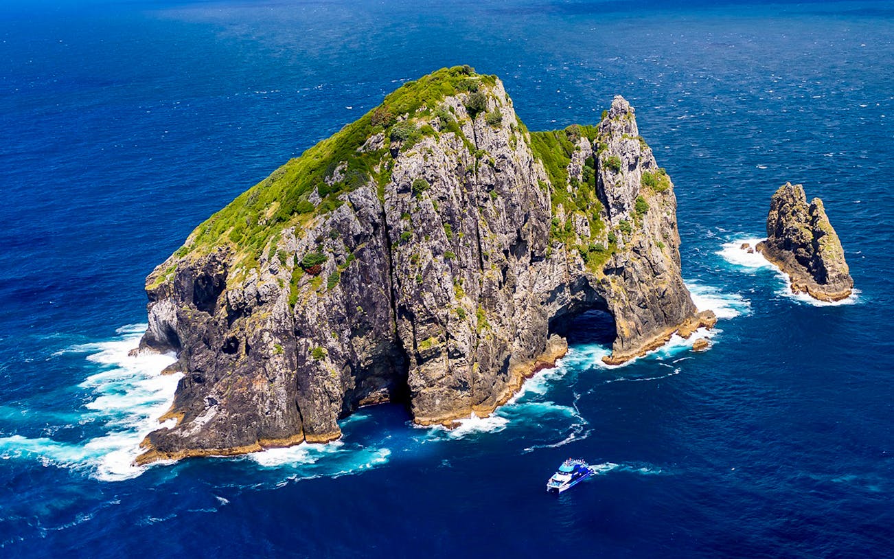 Bay of Islands rock formation with tour boat in ocean, New Zealand.