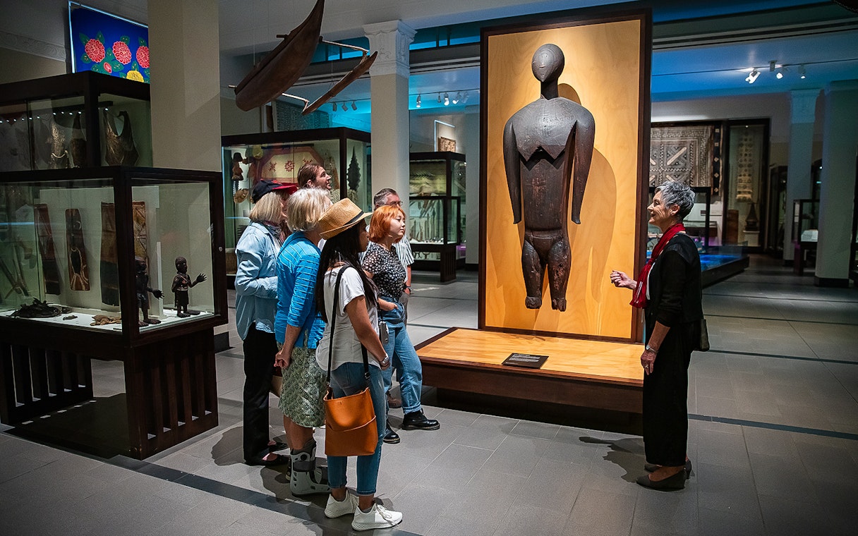 Visitors observing an exhibit during a guided tour at Auckland War Memorial Museum.