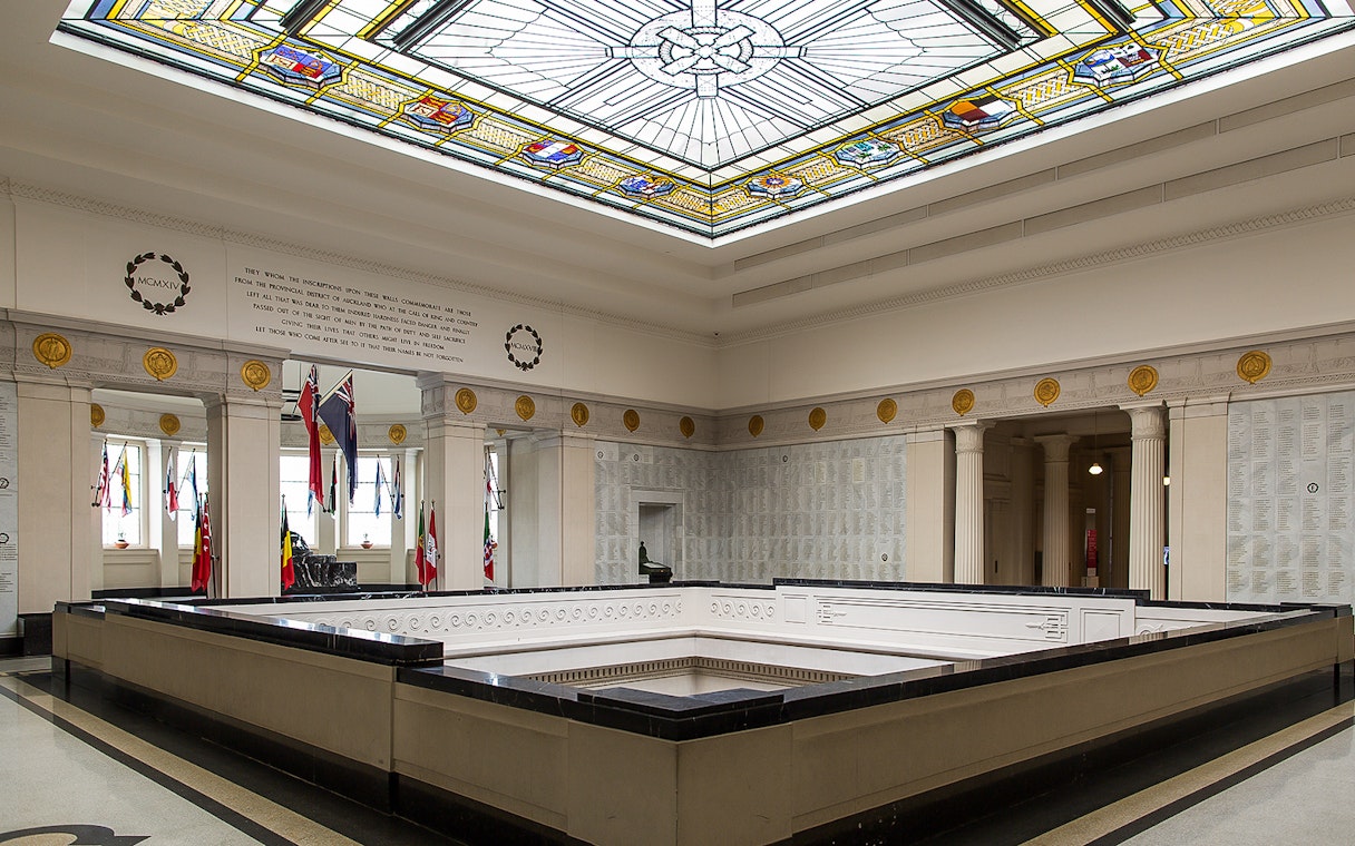 Auckland War Memorial Museum interior with stained glass ceiling and flags.