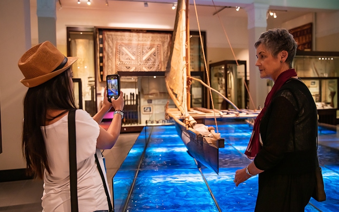Visitors exploring a traditional canoe exhibit at Auckland War Memorial Museum.