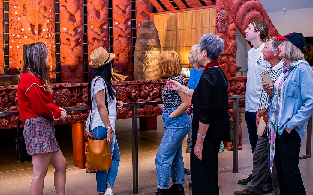 Visitors observing Maori carvings at Auckland War Memorial Museum.