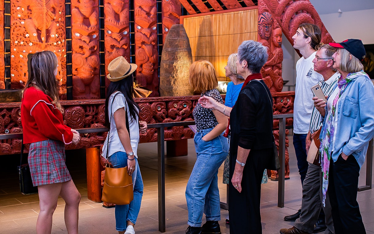 Visitors observing Maori carvings at Auckland War Memorial Museum.