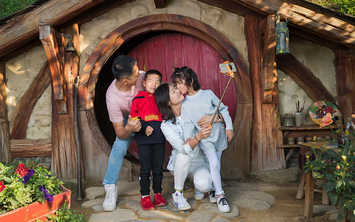 Family taking a selfie at Hobbiton Movie Set entrance, Rotorua tour.