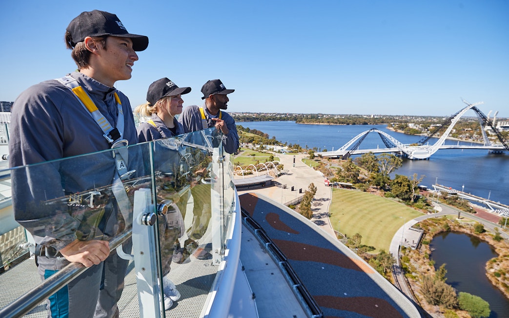 Visitors enjoying the view from Optus Stadium rooftop with Matagarup Bridge in Perth.