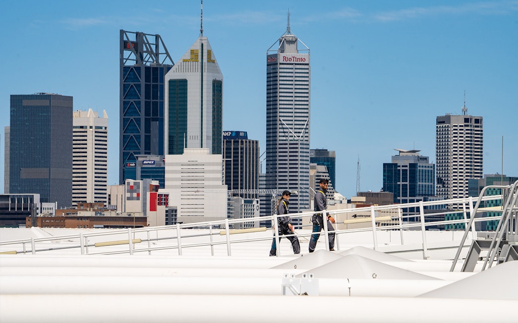 Visitors walking on Optus Stadium roof with Perth skyline in background.