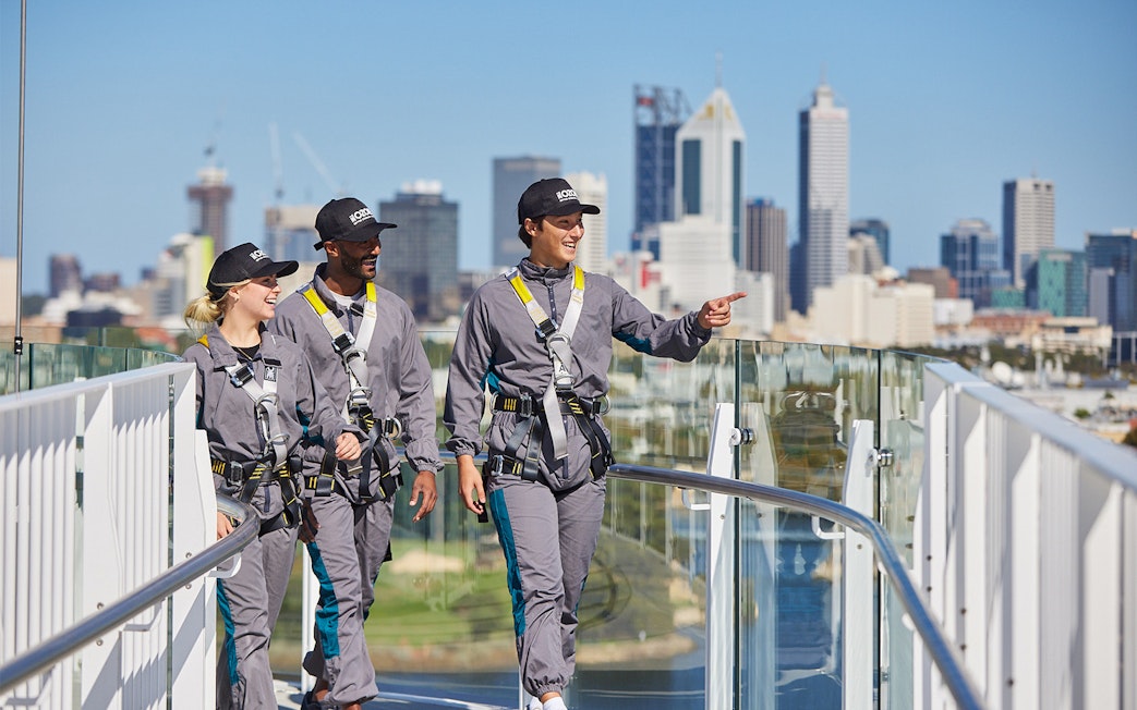 Tour group walking on Optus Stadium roof with Perth skyline in background.