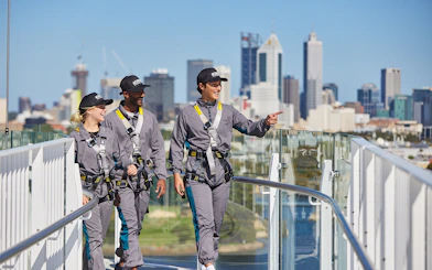 Tour group walking on Optus Stadium roof with Perth skyline in background.