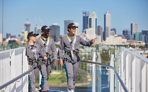 Tour group walking on Optus Stadium roof with Perth skyline in background.