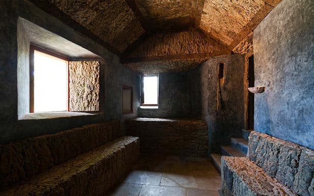 Convento dos Capuchos interior with stone benches and rustic walls, Sintra, Portugal.
