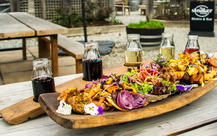 Gourmet platter with assorted vegetables and wine glasses on a Queenstown tour.