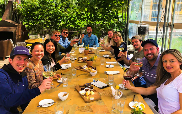 Group enjoying wine and cheese at a vineyard on a Queenstown gourmet tour.