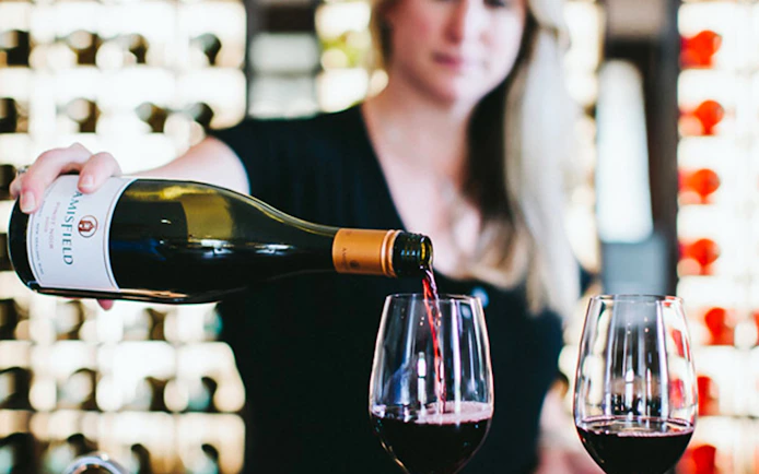 Pouring red wine into glasses on a Queenstown gourmet food and wine tour.