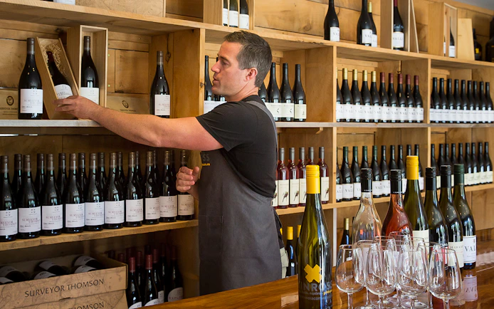 Man selecting wine bottle in Queenstown winery during gourmet food and wine tour.
