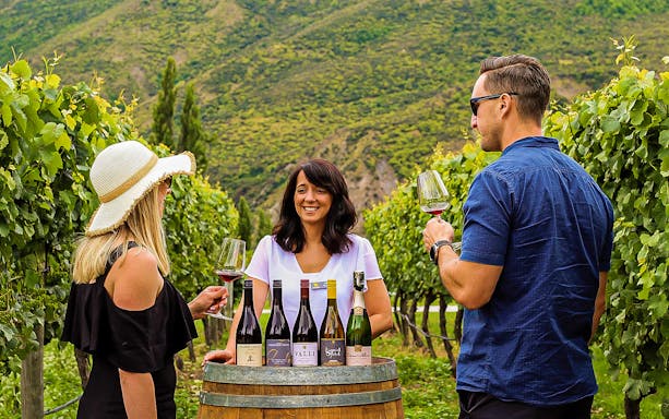 Wine tasting at a vineyard near Queenstown with bottles displayed on a barrel.