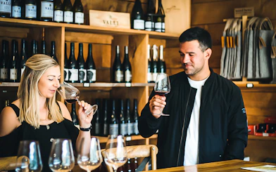 Wine tasting experience in Queenstown winery with two people sampling red wine.