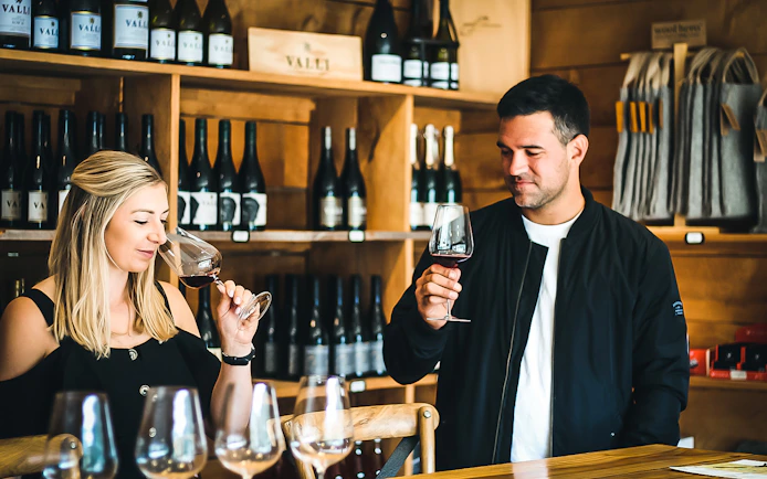 Wine tasting experience in Queenstown winery with two people sampling red wine.