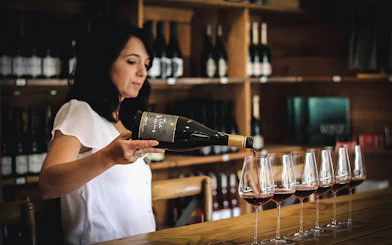 Pouring red wine into glasses during Queenstown gourmet tour.