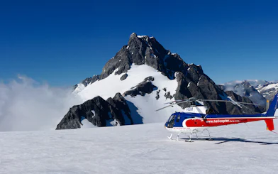 Helicopter on snowy alpine landing with mountain backdrop, Queenstown Panorama Tour.