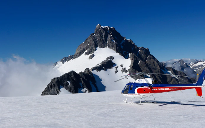 Helicopter on snowy alpine landing with mountain backdrop, Queenstown Panorama Tour.