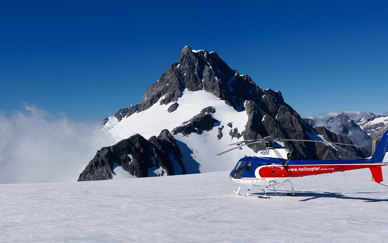 Helicopter on snowy alpine landing with mountain backdrop, Queenstown Panorama Tour.