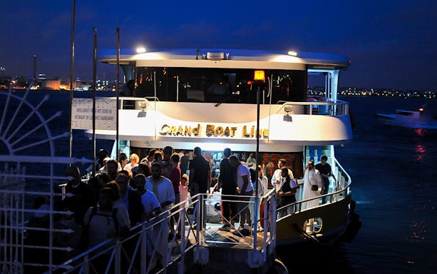 Tourists boarding a boat for a Bosphorus and Golden Horn cruise from Istanbul's Old City at night.