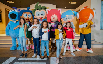 Children posing with Kidzania Dubai mascots indoors.