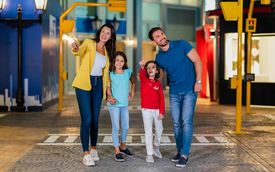 Family exploring KidZania Dubai, children pointing at attractions.